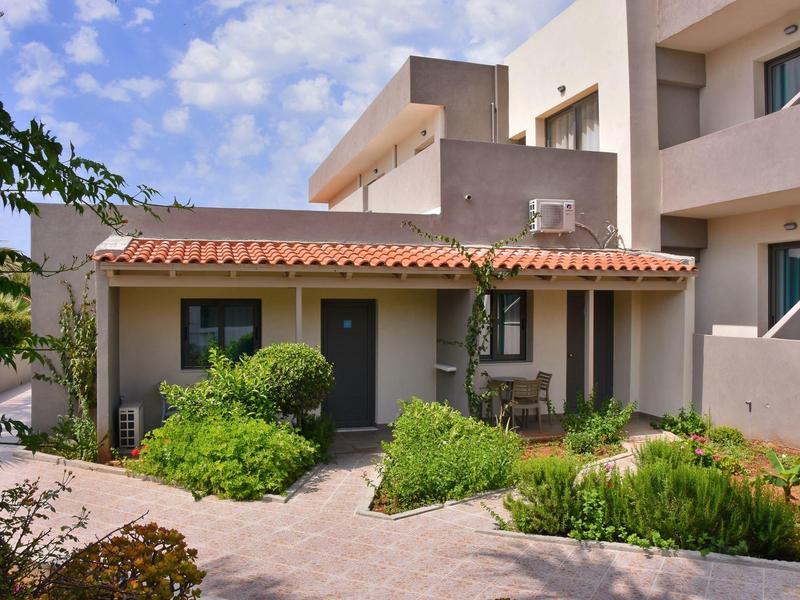 Moderní hotelová budova s upravenou přední zahradou a modrou oblohou v pozadí.