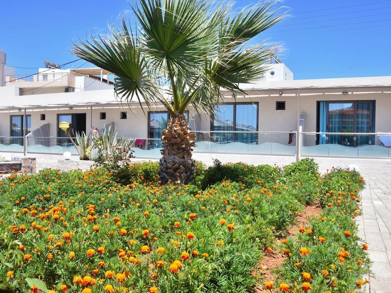 Moderní hotelový komplex s tropickou zahradou a palmami pod modrou oblohou.