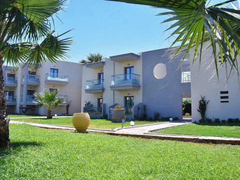 Moderní hotelový komplex s modrými stěnami, balkony a upravenou zahradou s palmami