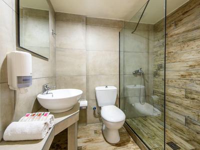 Modernes Badezimmer mit Toilette, rundem Waschbecken, Handtüchern und begehbarer Dusche mit Glaswand.