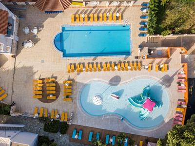 Luftaufnahme von zwei Schwimmbecken mit Wasserrutsche und gelben Liegestühlen darum.