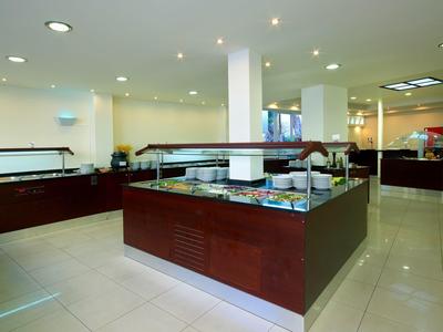 Buffetbereich mit Glasabdeckungen, weißer Decke, hellen Fliesen und Holzmöbeln.