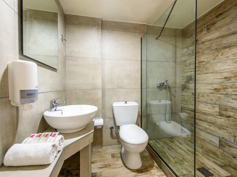 Moderne badkamer met wastafel, toilet en glazen douchecabine met hout-look tegels.