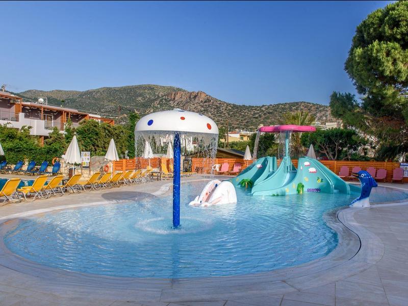 Kinderwaterplas met glijbanen, parasols en ligstoelen voor berglandschap