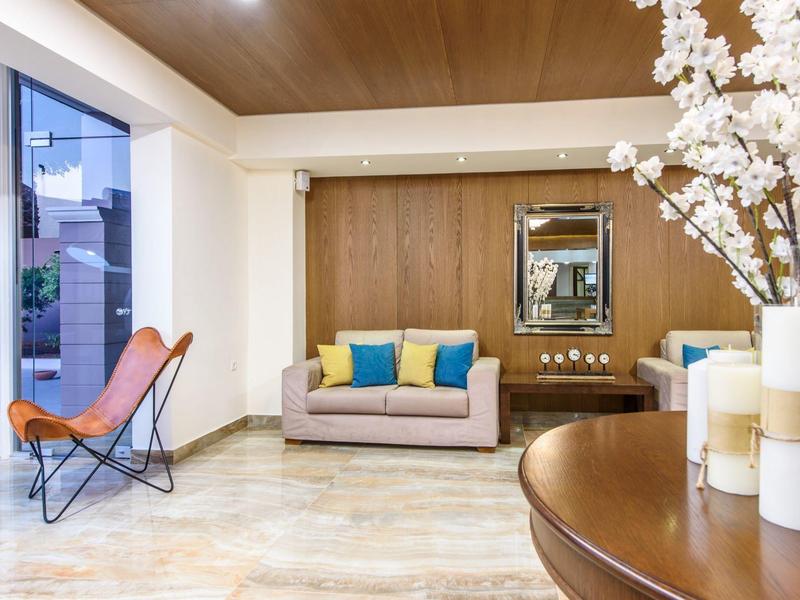 Moderne lounge met vlinderstoelen, bank met kleurrijke kussens en bloemendecor.