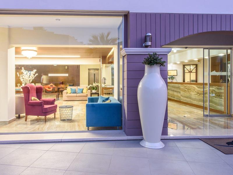 Uitzicht op een hotel-loungedeel met zitmeubilair en grote glazen gevel.