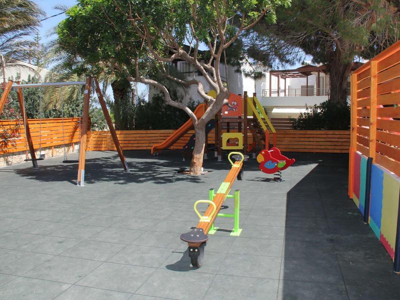 Kinderspeelplaats met schommels, wip en klimrek in een hotel binnenplaats.