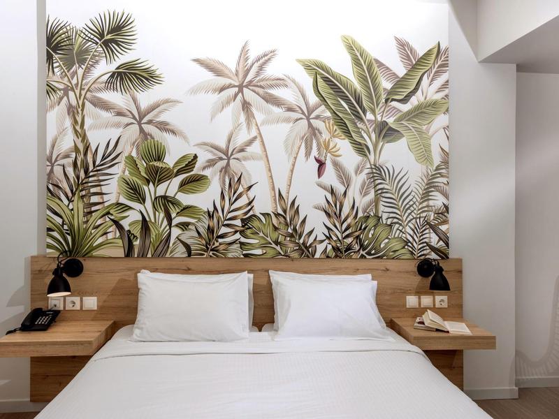 Moderne slaapkamer met tweepersoonsbed en tropische plantenmotief muurdecoratie.