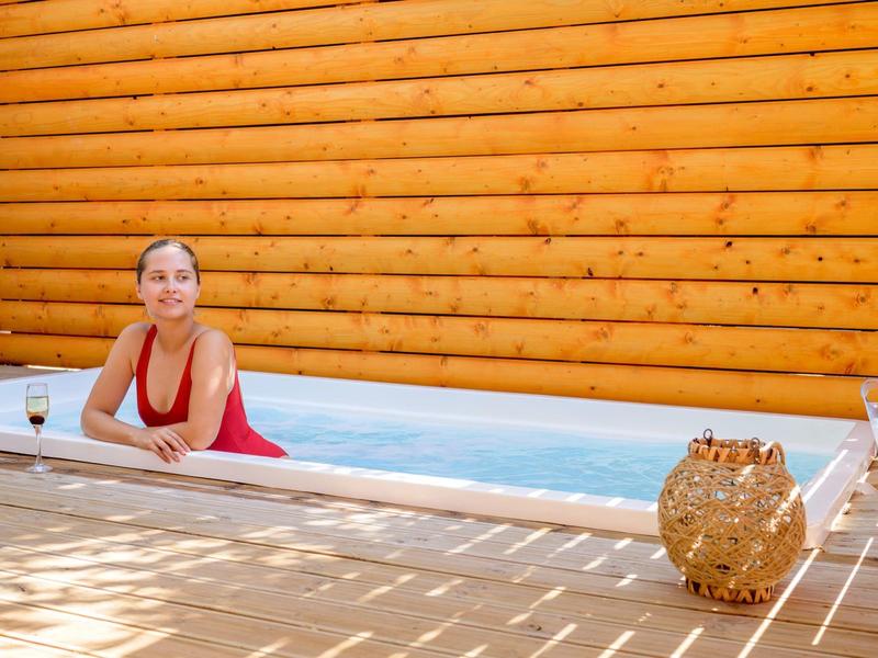 Vrouw ontspant in een zwembad van een blokhutsauna met houten vloer en lantaarn