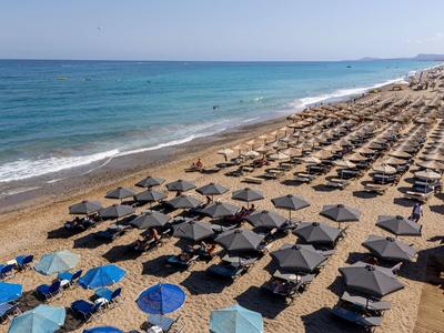 Spiaggia con numerosi ombrelloni e lettini vicino al mare turchese.