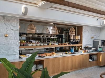 Buffet per la colazione con tostapane, cestini e tazze in una stanza luminosa con mobili in legno.