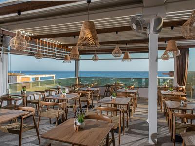 Ristorante aperto con mobili in legno e vista sul mare alla luce del giorno.