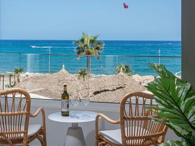 Terrazza con due sedie e tavolo con vista mare e palma.