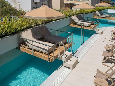 Piscina con lettini sospesi e posti a sedere vicino a un hotel moderno