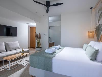 Camera d'hotel moderna con letto matrimoniale, divano, TV e decorazione minimalista.