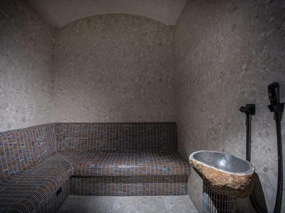 Sauna accogliente in pietra con area salotto e lavabo.