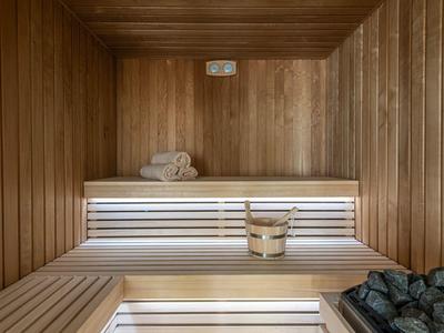 Sauna interna con pannelli in legno, panche, secchio e asciugamani.