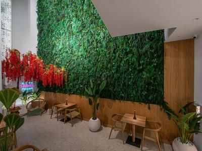 Interno moderno con parete di piante verdi, mobili in legno e piante sospese.