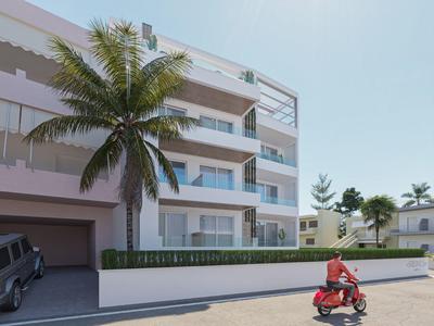 Moderner weißer Wohnblock mit Balkonen, Palmen davor und rotem Lieferroller auf der Straße.
