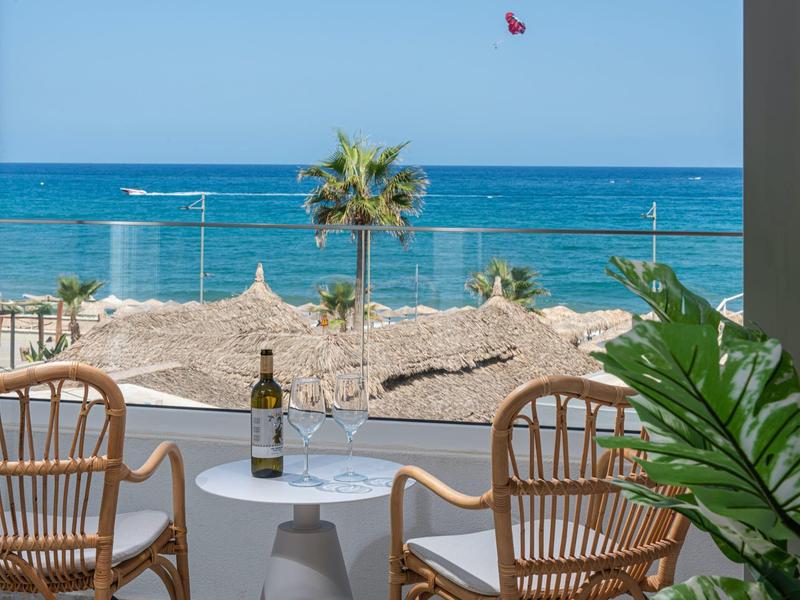 Terrazza con due sedie e tavolo con vista mare e palma.
