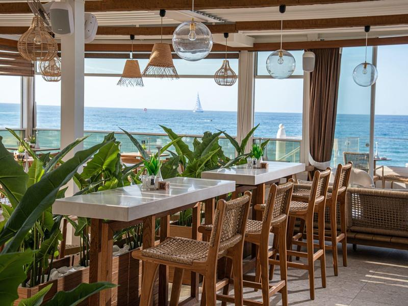 Ristorante con tavoli e sedie in legno con vista sul mare.