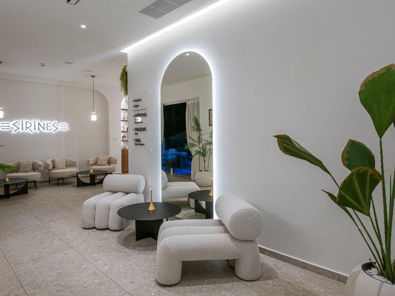 Area di accoglienza luminosa con interni bianchi moderni e grandi piante.