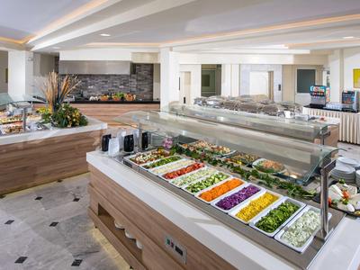 Area buffet con insalate di verdure fresche e un design interno moderno e luminoso.
