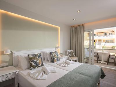 Camera d'hotel moderna con due letti, cuscini decorativi e balcone con mobili da esterno.