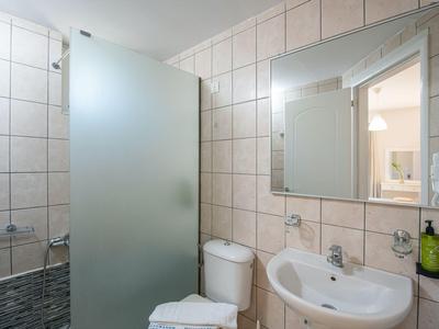 Piccolo bagno con lavabo, WC e doccia con divisorio in vetro smerigliato.