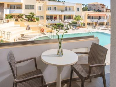 Tavolo da balcone con due sedie con vista su piscina e edificio dell'hotel.