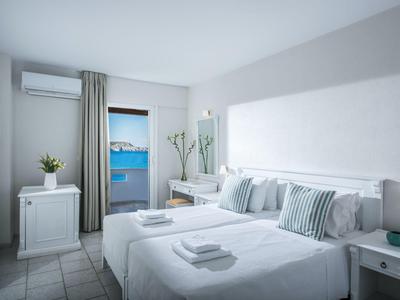 Camera d'hotel luminosa con due letti singoli, ambiente pulito e vista sul mare.