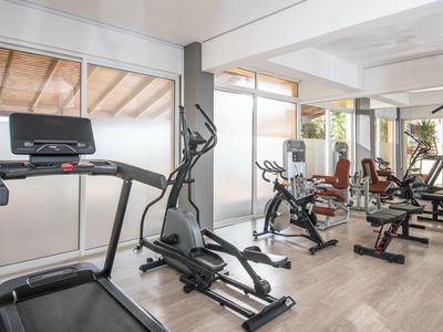 Sala fitness con tapis roulant, ellittiche e altre attrezzature in uno spazio luminoso.