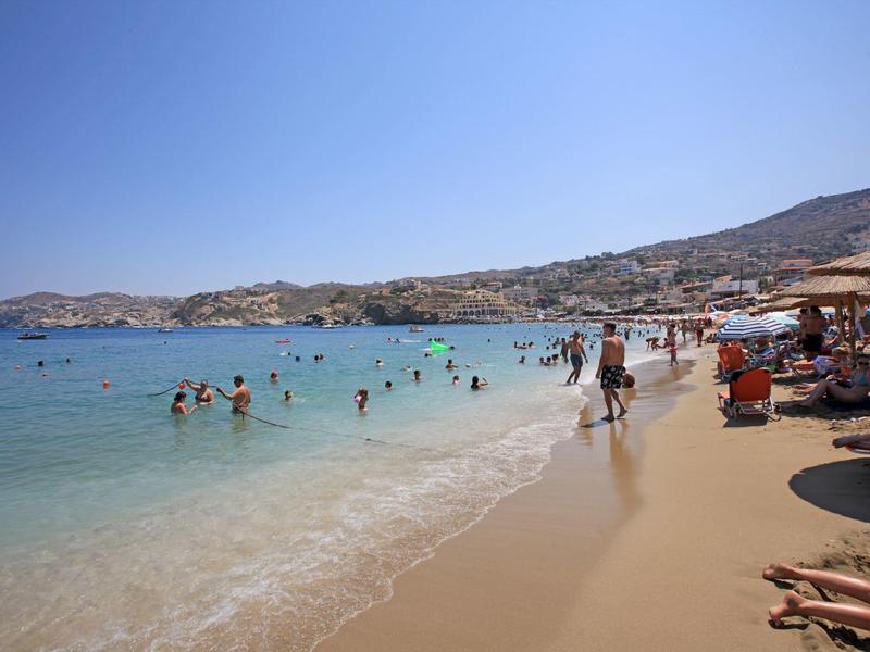 Des gens profitent d'une plage ensoleillée avec de l'eau claire et un ciel bleu.