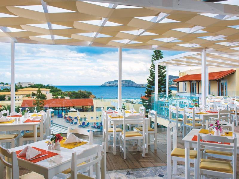 Restaurant ouvert et lumineux avec vue sur la mer et les bâtiments environnants.