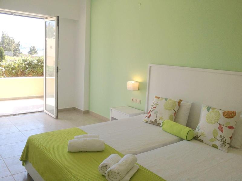 Chambre d'hôtel lumineuse avec accents verts, lit double et accès balcon ou terrasse