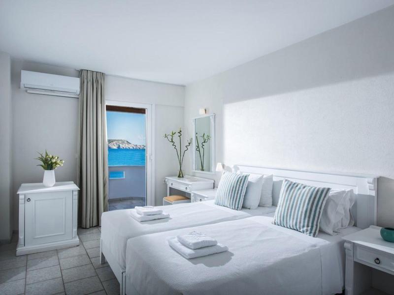 Chambre d'hôtel moderne avec deux lits simples et vue sur la mer.