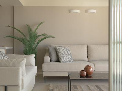 Sala moderna con sofás beige, cojines y cerámicas sobre la mesa de centro.