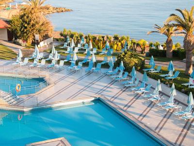 Zwembadgebied met ligstoelen en parasols aan het water bij een hotelresort.