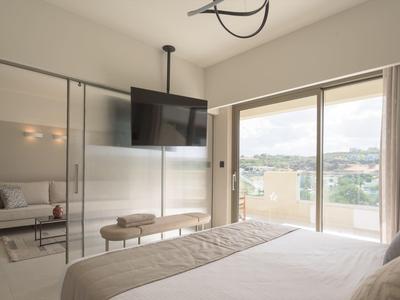 Habitación de hotel luminosa con cama king, televisor de pantalla plana y balcón con vista.