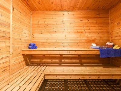 Habitación de sauna cálida de madera con bancos y toallas en una repisa.