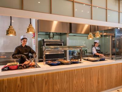Twee koks bereiden eten bij een buffet in een modern restaurant.