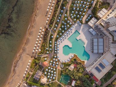 Luchtfoto van een hotel met zwembad, parasols en strand langs de kust.