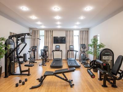 Moderne fitnessruimte met apparaten, halters en houten vloer in een hotel.