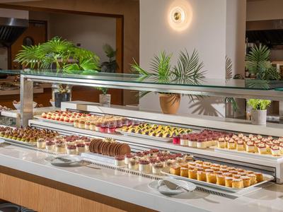 Bedieningsbuffet met een verscheidenheid aan kleine, decoratieve desserts op wit marmer.