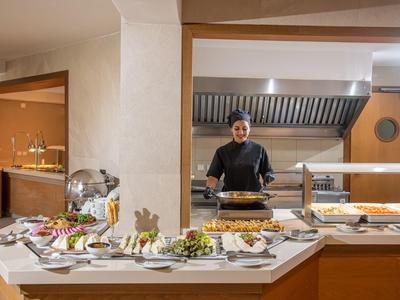 Hotel restaurantbuffet met diverse gerechten en een kok op de achtergrond.