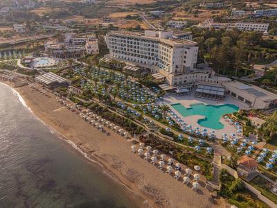 Luxe hotel aan een zandstrand met zwembad en parasols.
