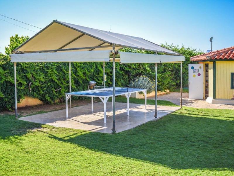 Carpa blanca con mesas al aire libre en un jardín bien cuidado junto a una casa amarilla