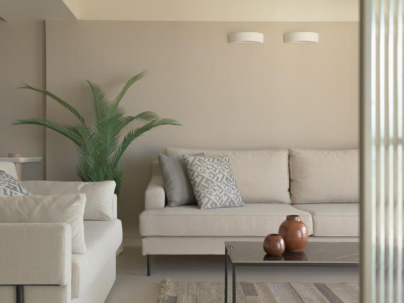 Sala moderna con sofás beige, cojines y cerámicas sobre la mesa de centro.