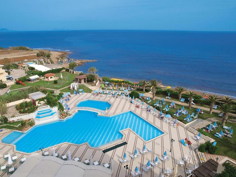 Gran área de piscina con tumbonas y vista al mar en un resort.