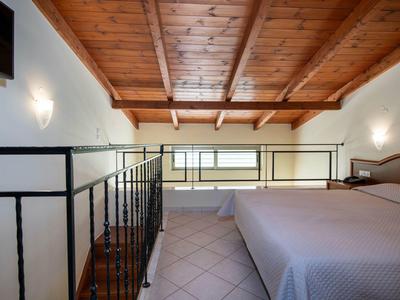 Gemütliches Schlafzimmer mit Holzbalkendecke, großem Bett und einem kleinen Fenster an der Wand.